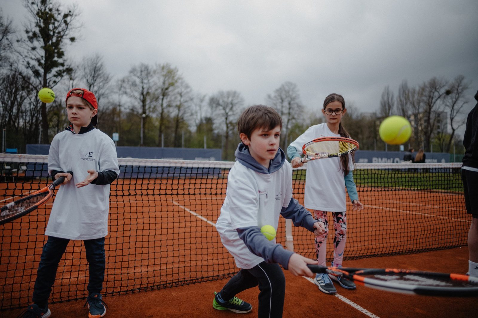 Kinder auf einem Sandplatz bei einem Tennis-Camp der Foundation