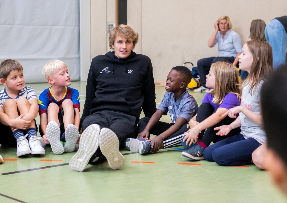 Eine Gruppe Kinder jubelt mit erhobenen Armen in einer Sporthalle